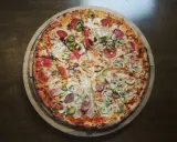 Cała pizza z różnymi dodatkami: salami, pieczarki, kukurydza, papryczki jalapeno i ogórek.