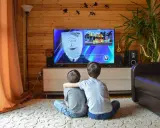 Dwóch chłopców ogląda bajkę w telewizji, która może być szkodliwa dla dzieci. Na ekranie postać z workiem na głowie i napis "HOUSE FIRE!".