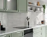 Jasne, błyszczące płytki między szafkami w kuchni dodają elegancji.
