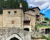 Antico ponte in pietra e case in pietra, tipici dei borghi vicino Arezzo, immersi nel verde della campagna toscana.