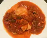 Un plato de urta a la roteña, con trozos de pescado blanco en una salsa roja de tomate y verduras.