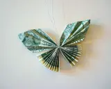 Schmetterling aus gefalteten Geldscheinen, kunstvoll arrangiert. Die feinen Knicke der Geldscheine formen zarte Flügel.