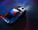 Der BMW M4 GT3 in dynamischer Motorsport-Lackierung steht bereit für die Rennstrecke, beleuchtet von Scheinwerfern.