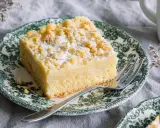 Ein Stück Streuselkuchen ohne Hefe, bestäubt mit Puderzucker, auf einem Teller mit grünem Muster.