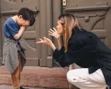 Madre explica a su hijo cómo poner límites a los niños. El niño se tapa la cara con las manos, visiblemente afectado.