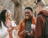 Trzech przyjaciół śmieje się, trzymając telefony. Może to być moment, gdy szukają wskazówek, jak wyjść z friendzone.