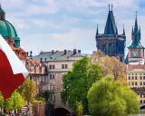 Flaga Czech powiewa nad Pragą, ukazując ciekawe fakty o Czechach. W tle widać Most Karola i wieże.