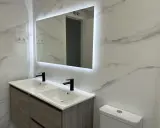 Moderno lavabo doble con grifería negra y espejo iluminado. Una solución ideal para reformar baño sin obras, con un toque de elegancia.