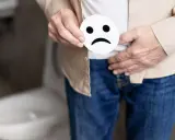 Osoba trzyma smutną buźkę, wskazując na dyskomfort związany z zapaleniem ujścia cewki moczowej.
