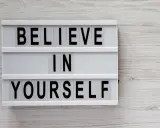 Biała tablica z czarnymi literami: "BELIEVE IN YOURSELF". To przesłanie inspiruje do nastawienia na rozwój i wiary we własne możliwości.