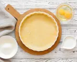 Préparation d'une pâte sucrée pour une tarte. Ingrédients : pâte dans un moule, œufs, sucre, lait.