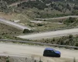 Coche azul en carretera de montaña con curvas pronunciadas. Podría recibir una multa por circular por pista forestal.
