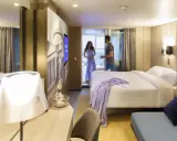 Coppia in una moderna cabina interna di Costa Crociere. Letto matrimoniale, decorazioni artistiche e un balcone invitano al relax.