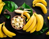 Pęki dojrzałych bananów, jeden obrany i pokrojony w miseczce. Zastanawiasz się, ile węglowodanów ma banan?