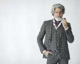 Distinguished gentleman in a plaid suit, vest, and ascot, holding a pipe. The perfect father of the groom attire.