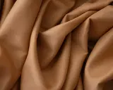 Tessuto in crepe color caramello, ideale per abiti eleganti, sia estivi che invernali, grazie alla sua caduta fluida.
