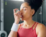 Frau mit Inhalator im Fitnessstudio. Sport bei COPD kann mit richtiger Vorbereitung möglich sein.