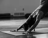 En person utför en nedåtgående hund-position under kundalini yoga.