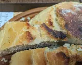 Ein knuspriges, goldbraunes dutch oven brot mit einer luftigen Krume, auf einem Holzbrett serviert.