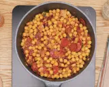 Garbanzos fritos con chorizo y bacon en sartén, listos para servir. Un plato sabroso y reconfortante.
