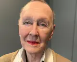 Åldfrun Ebba von Mecklenburg, med sina blå ögon och röda läppar, bär en beige kofta och ett pärlhalsband.