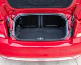 Maletero abierto de un Fiat 500 rojo, mostrando el espacio de carga cubierto de fieltro oscuro.