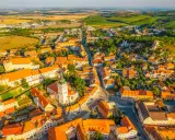 Malownicze miasteczko na Morawach w Czechach, z dominującą wieżą kościelną i pomarańczowymi dachami, otoczone zielonymi wzgórzami.