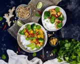 Zwei Schüsseln mit Reis, Tofu, Brokkoli und Erbsen. Ein Gericht, das vegan und proteinreich ist, mit Ingwer, Chili und Koriander garniert.