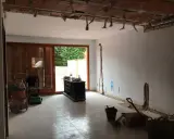 Interior de una casa de pueblo en plena reforma. Se ven materiales de construcción, herramientas y un aspirador.