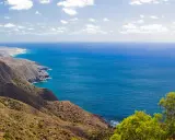 Blick auf die zerklüftete Küste und das tiefblaue Meer bei Cabo de Palos. Grüne Vegetation bedeckt die Hügel, die zum Meer abfallen.