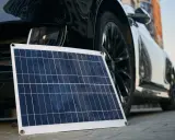 Panel solar portátil junto a un coche eléctrico, listo para cargar en casa.
