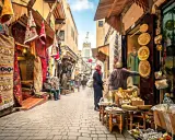 Bunte Teppiche und Souvenirs säumen einen belebten suk markt. Menschen schlendern durch die Gasse, vorbei an Geschäften voller Schätze.