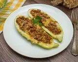 Dos mitades de calabacines rellenos de carne picada y queso gratinado, decorados con perejil. Un plato casero y delicioso.