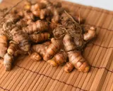 Kłącza kurkumy, znanej jako turmeric co to, leżą na bambusowej macie.