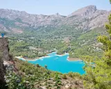 Espectacular vista de la ruta pueblos interior Alicante, con un embalse turquesa rodeado de montañas y vegetación.