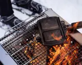 En smörgåsgrill värms över en eld, perfekt för friluftsmat recept i snön.