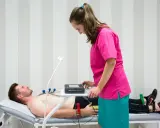 Mężczyzna leży na kozetce, pielęgniarka przygotowuje mu ekg spoczynkowe. Ile trwa badanie? Krótko, by ocenić pracę serca.