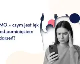 Młoda kobieta zmartwiona przegląda telefon, podczas gdy w tle widać sylwetki bawiących się ludzi. FOMO - czym jest lęk przed pominięciem wydarzeń?