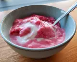 En skål med krämig rabarbercurd med en virvel av grädde. Perfekt för en somrig fika.