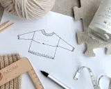 Esquema de jersey con medidas, ovillo de lana, agujas, cinta métrica y regla. Ideal para un top crochet tutorial.