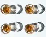 Vier Gläser mit bernsteinfarbenem Whiskey, die im Sonnenlicht stehen. Ein Vergleich zwischen Bourbon vs. Whiskey.