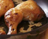 Cosce di pollo dorate e succulente cuociono in padella, emanando un profumo invitante.