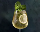 Un verre de Hugo Spritz rafraîchissant, garni de menthe fraîche et d'une tranche de citron. Parfait pour une recette d'été.