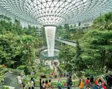 Imponerande vattenfall och frodig grönska under glastaket på singapore flygplats. Människor njuter av den unika miljön.