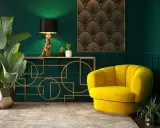 Eleganckie wnętrze w stylu art deco nowoczesny: złoty kot jako lampa, żółty fotel i geometryczne zdobienia na zielonej ścianie.