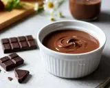 Un bol de crème chocolat onctueuse, entouré de morceaux de chocolat noir et de fraises. Un délice gourmand.
