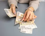 Dłonie liczą banknoty 200 zł. To może być wypłata świadczenia urlopowego na wymarzone wakacje.