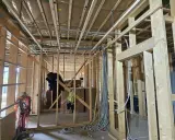 Widok wnętrza domu drewnianego w budowie. Widoczna instalacja elektryczna, drewniane ściany i stropy. Przepisy dotyczące instalacji elektrycznej w domach drewnianych są kluczowe dla bezpieczeństwa.