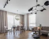 Nowoczesne oświetlenie salonu z jadalnią: designerski żyrandol i reflektory nad stołem. Aranżacje wnętrz z klasą.