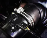 Detalle de un sensor MAF negro conectado a un tubo de admisión de aire. Este componente es clave para saber qué es el sensor MAF y cómo optimiza el rendimiento del motor.
